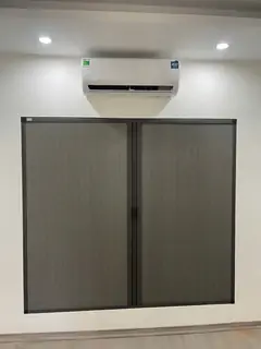 Vách tổ ong màu ghi hai cánh lắp vào ô tường bên dưới máy điều hoà