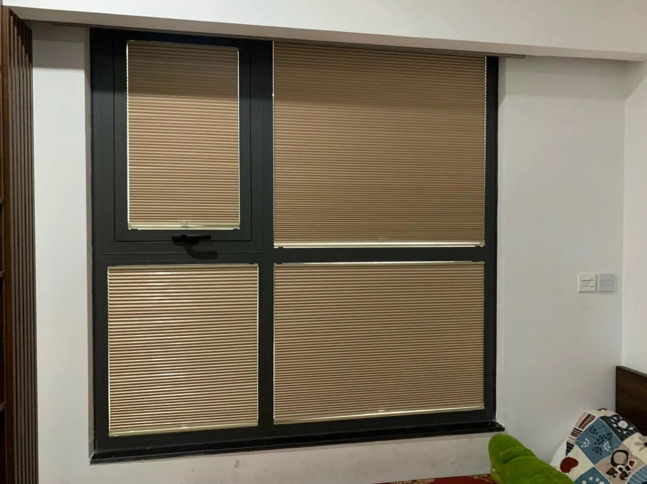 Cửa sổ chia bốn ô kính, mỗi ô lắp rèm màu be kéo ở độ cao khác nhau