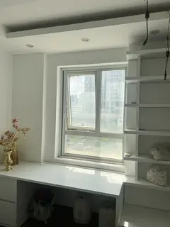 Cửa sổ phía trên bàn học gắn kệ trắng khi rèm đã thu lên