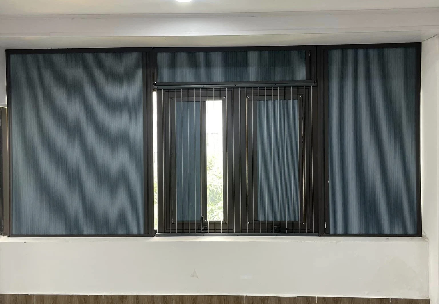 Dãy cửa sổ lắp rèm màu xanh xám, ô giữa kéo lên để lấy sáng