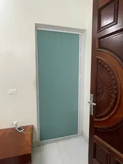 Rèm màu xanh ngọc kéo kín ô cửa đi phía sau cánh cửa gỗ