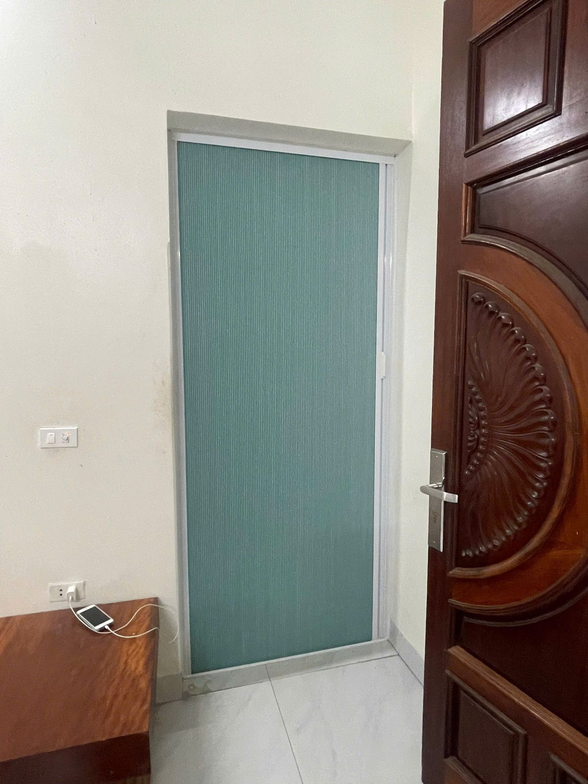 Rèm màu xanh ngọc kéo kín ô cửa đi phía sau cánh cửa gỗ