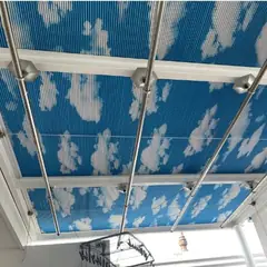 Rèm tổ ong in hình mây trời dưới mái kính giếng trời, có thanh căng inox