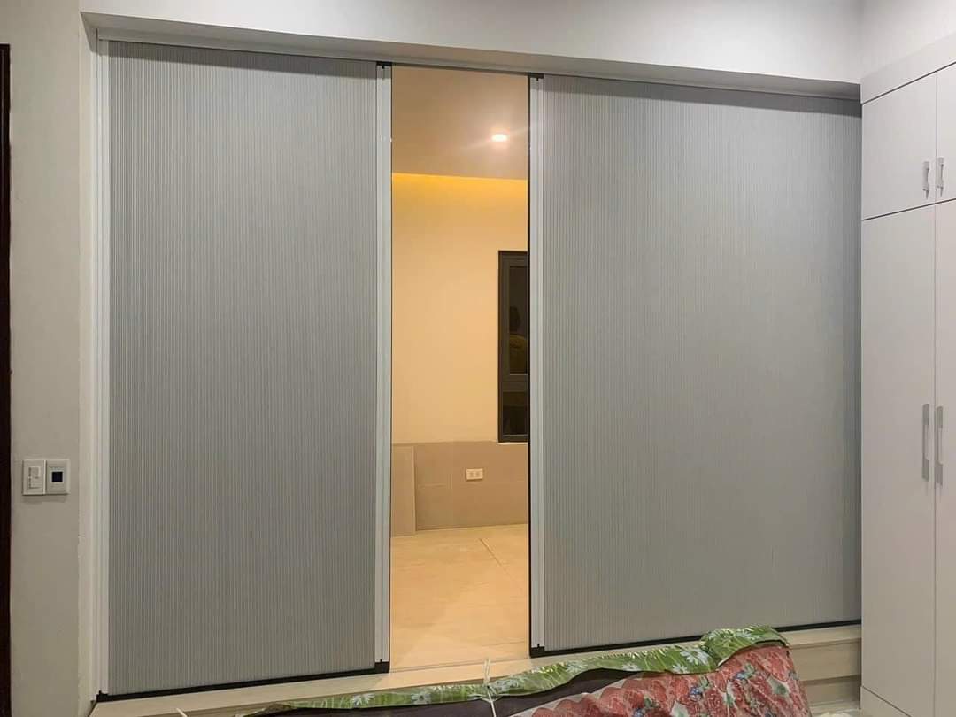 Vách ngăn màu ghi bạc hai cánh mở một lối vào phòng ngủ, bên cạnh tủ trắng