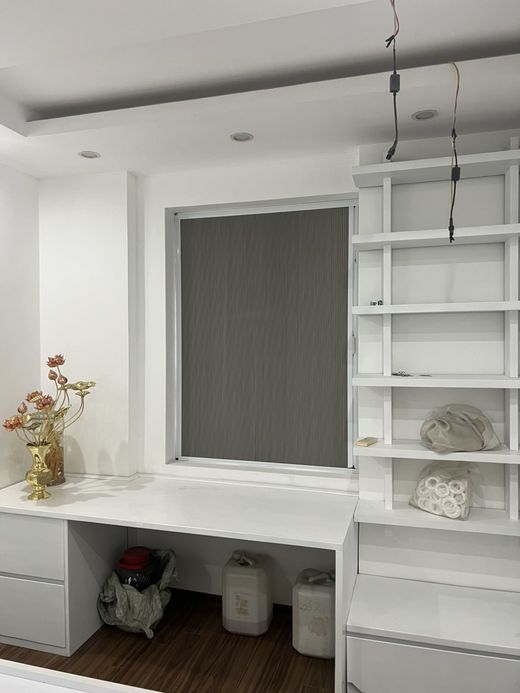 Rèm màu ghi kéo xuống ô cửa sổ phía trên bàn học gắn kệ trắng