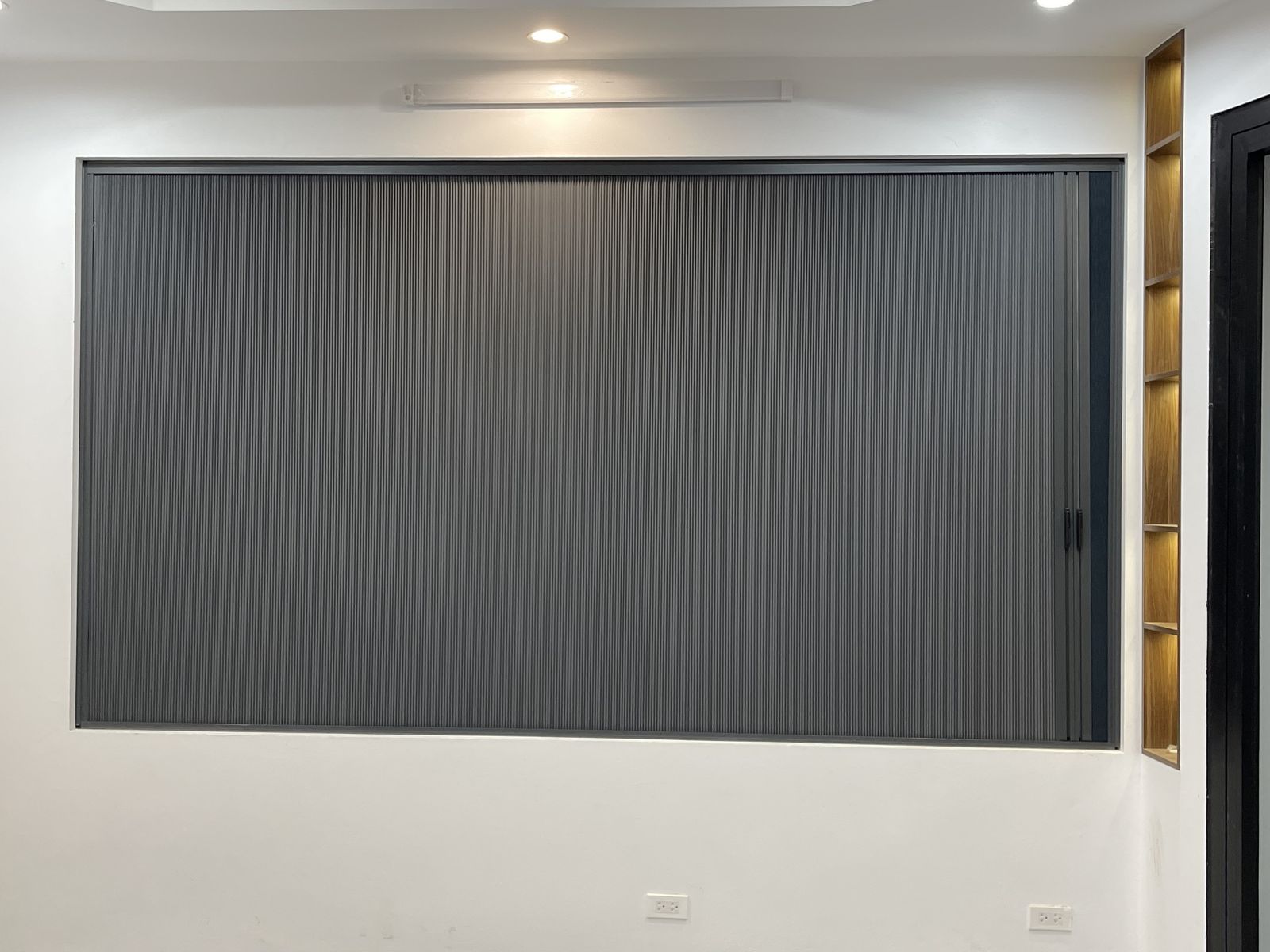 Rèm màu ghi đậm che kín ô cửa sổ lớn, kệ gỗ bên phải
